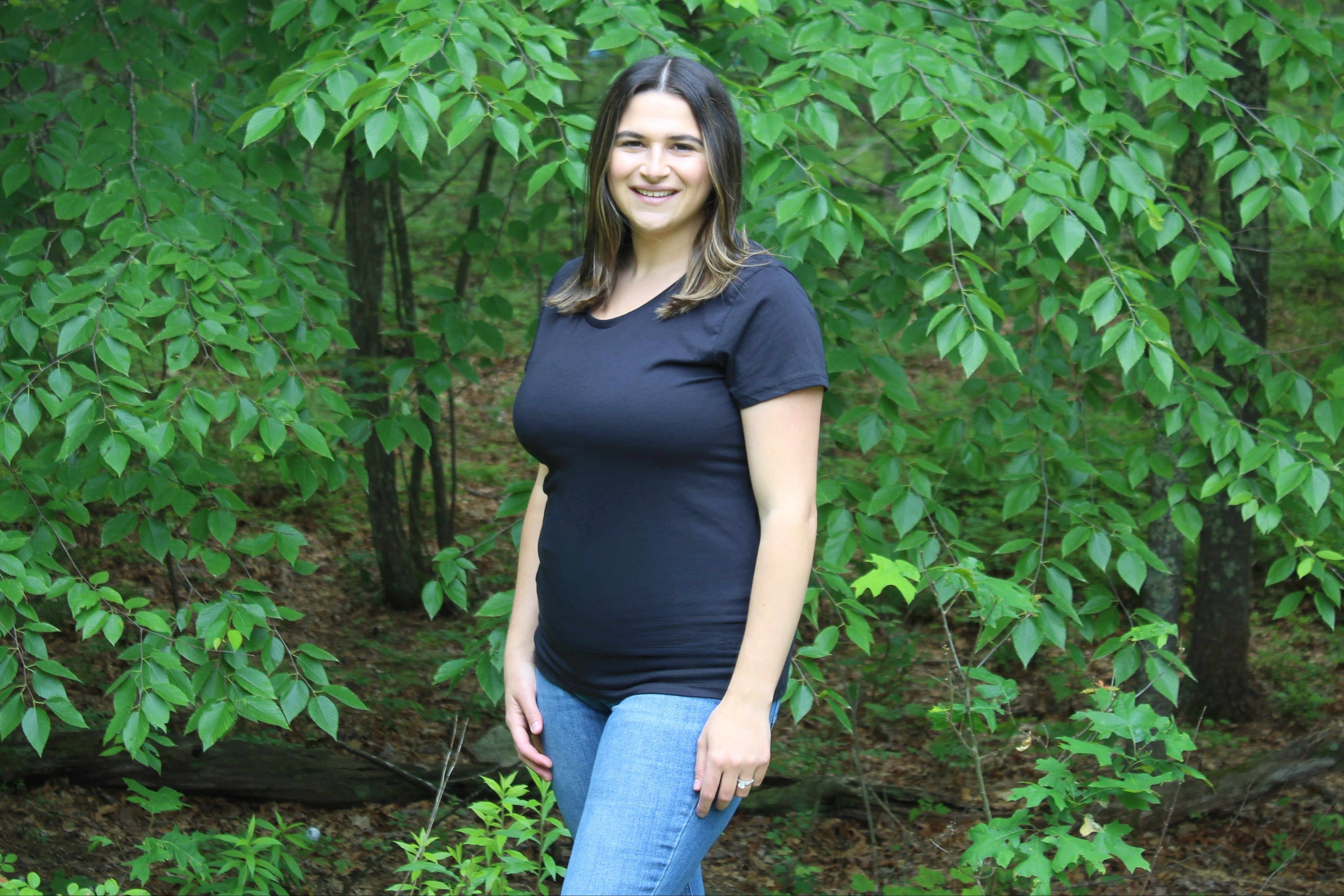 Woman wearing a black organic cotton tee in a lush outdoor setting, showcasing durability and comfort.