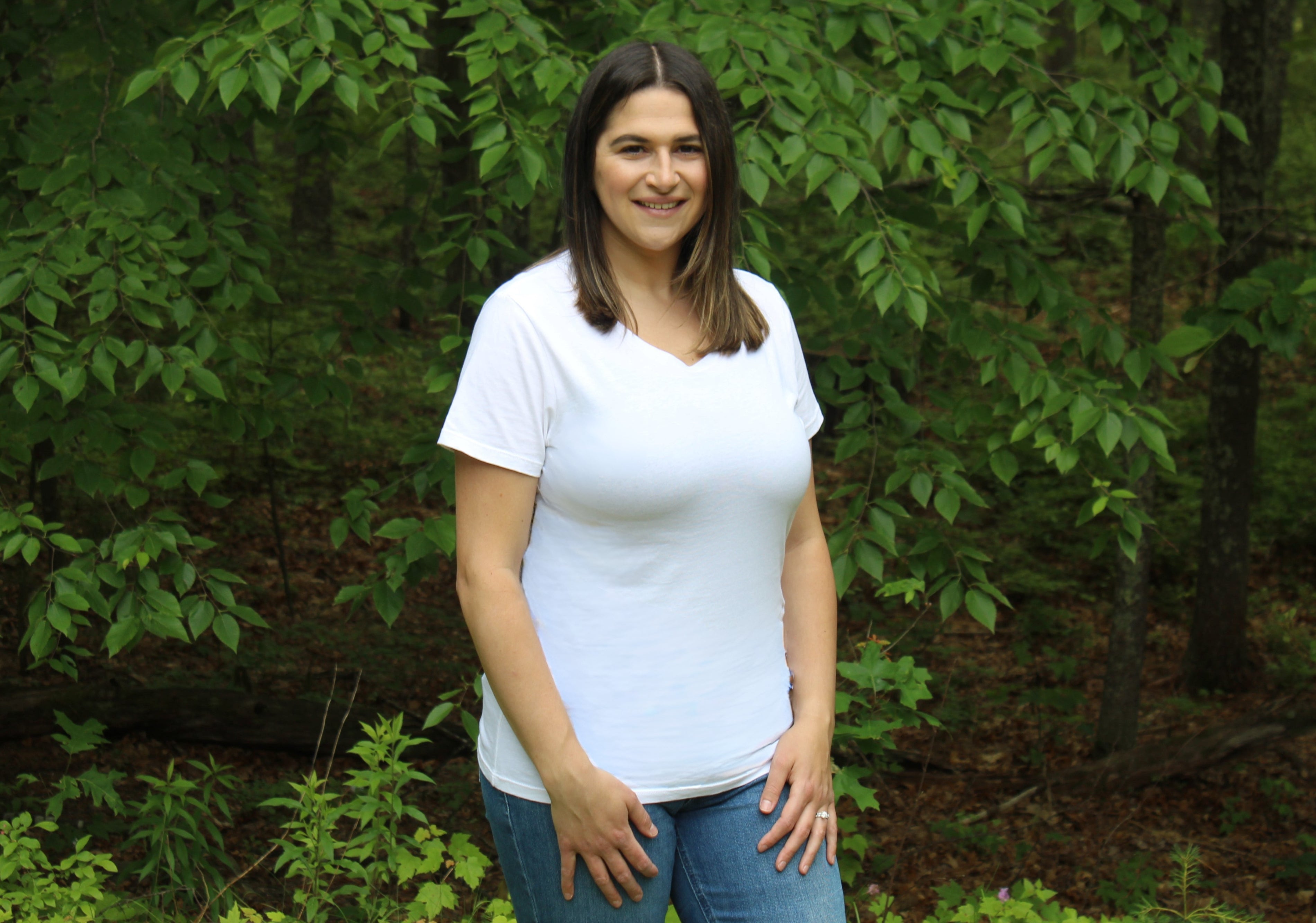Woman wearing a white fitted tee in a lush green outdoor setting, showcasing comfort and style.